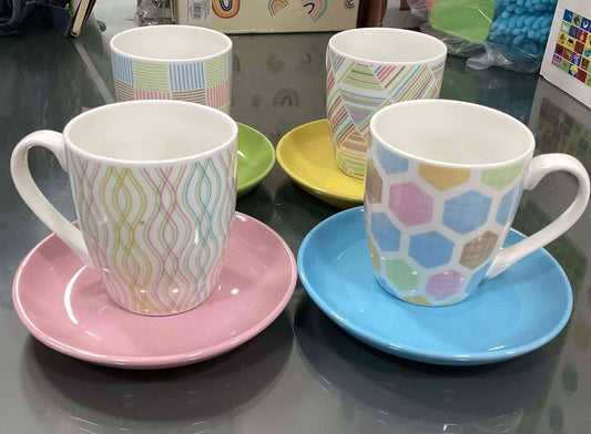 Set of 4 jumbo coffee cups with colorful geometric patterns and matching saucers in pink, blue, yellow, and green. Durable and stylish drinkware for home or office.